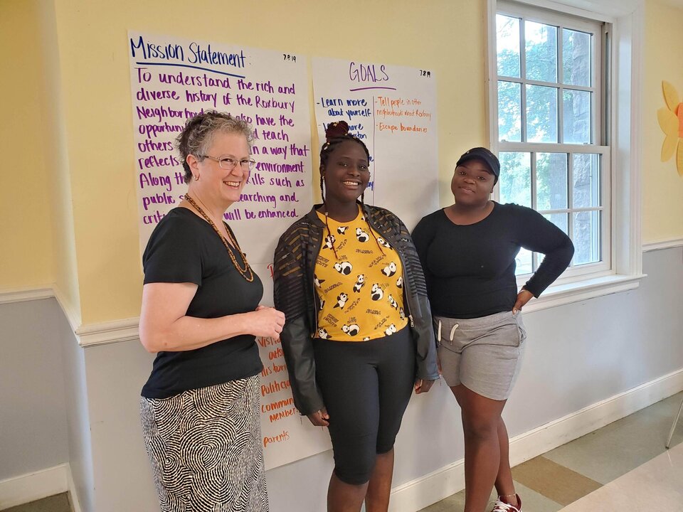 Tour Guides standing by a sign indoors