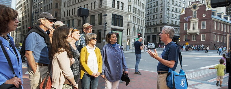 Don giving a tour to a small crowd of people in front of the old state house boston