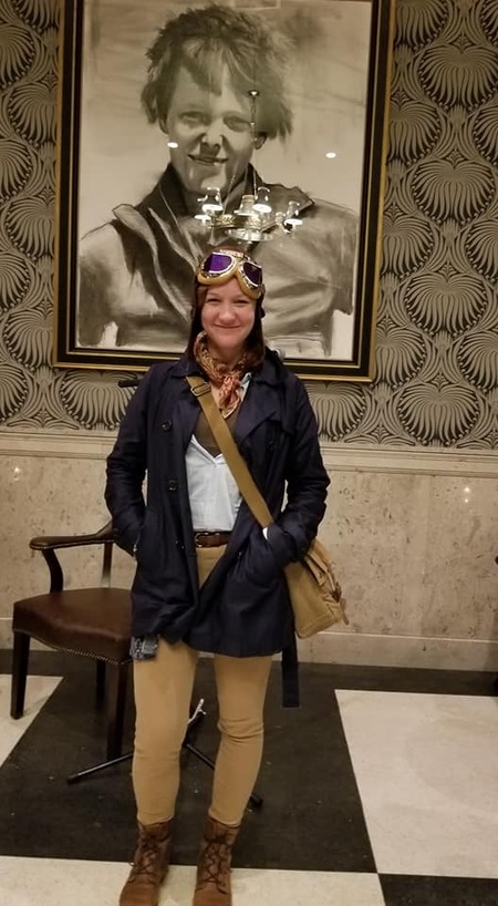 amelia the tour guide dressed as amelia earhart danding in front amelia earharts portrait