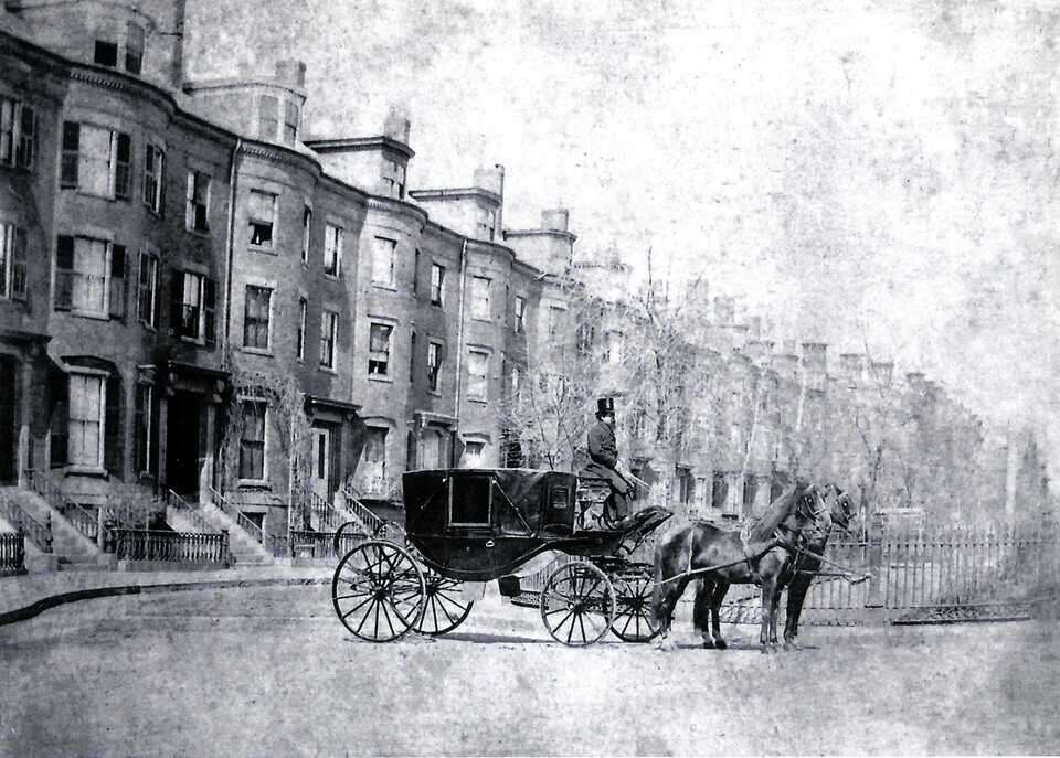 Horse drawn carriage with driver by row houses